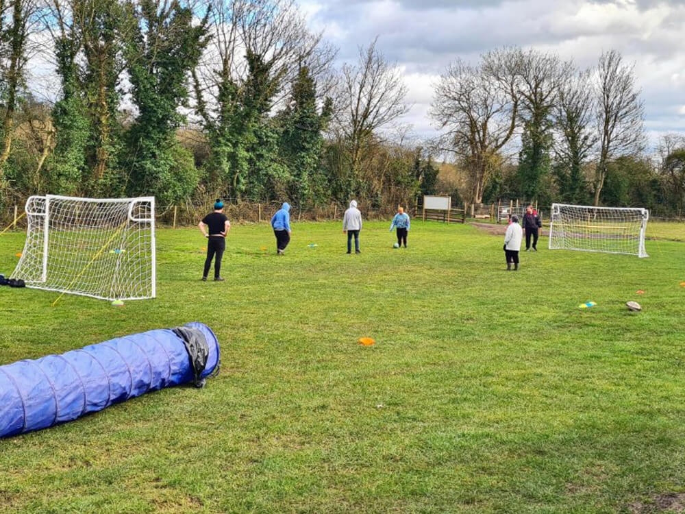 Group of adults playing football in a field on a cloudy day.