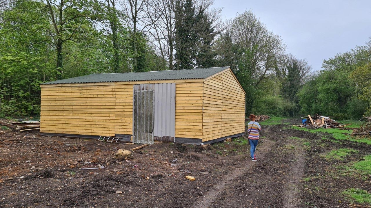Wooden building completed in muddy field.