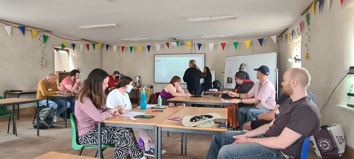 Group of adults sat at tables in classroom environment.