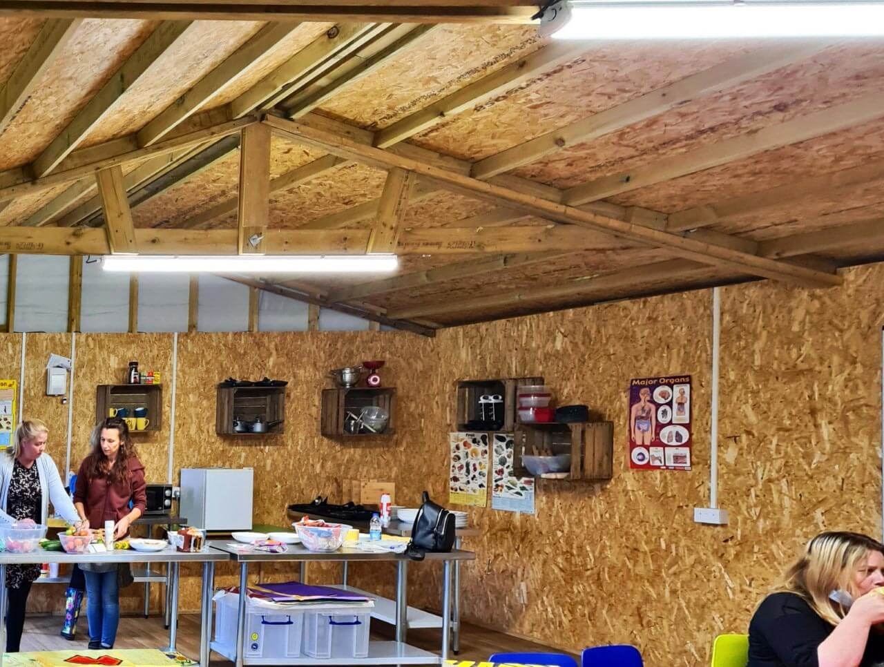 People in a work shop inside wooden building.