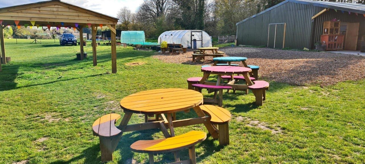 Wood stock community outdoor seating area with colourful picnic benches.